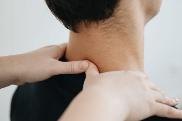 Close-up of a physiotherapist providing neck massage for pain relief in a clinic setting.