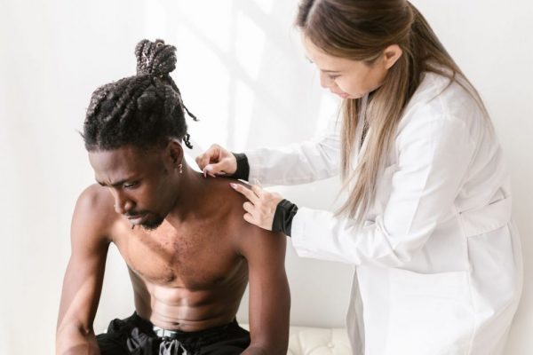 A therapist performs acupuncture on a patient for pain relief in a modern setting.