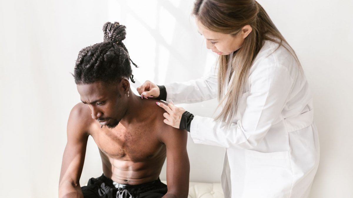 A therapist performs acupuncture on a patient for pain relief in a modern setting.