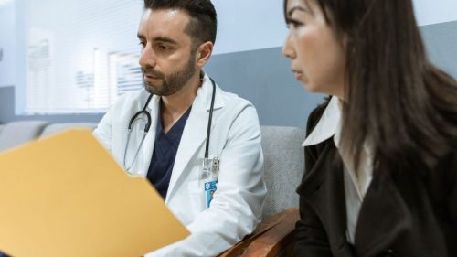 Doctor discusses health records with a patient in a clinical setting.