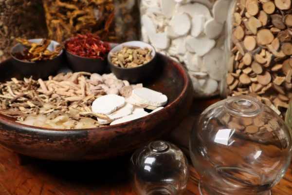 Close-up of herbal ingredients and glass jars used in traditional Chinese medicine therapy.